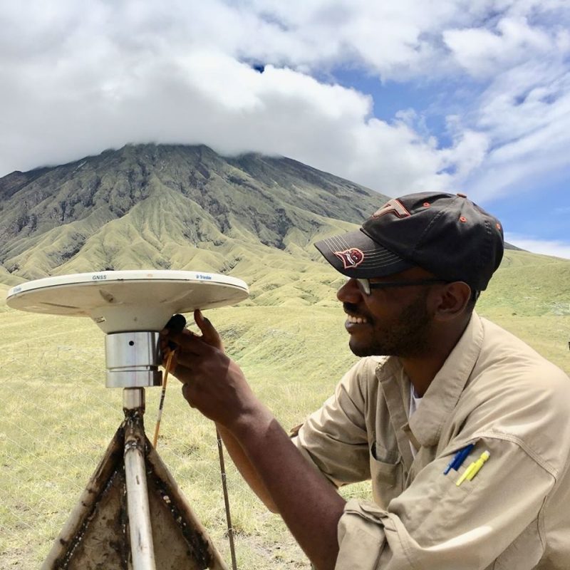 Josh fixing equipment with large Tanzanian volcano in background