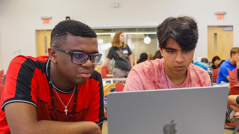 3 male students look at computer