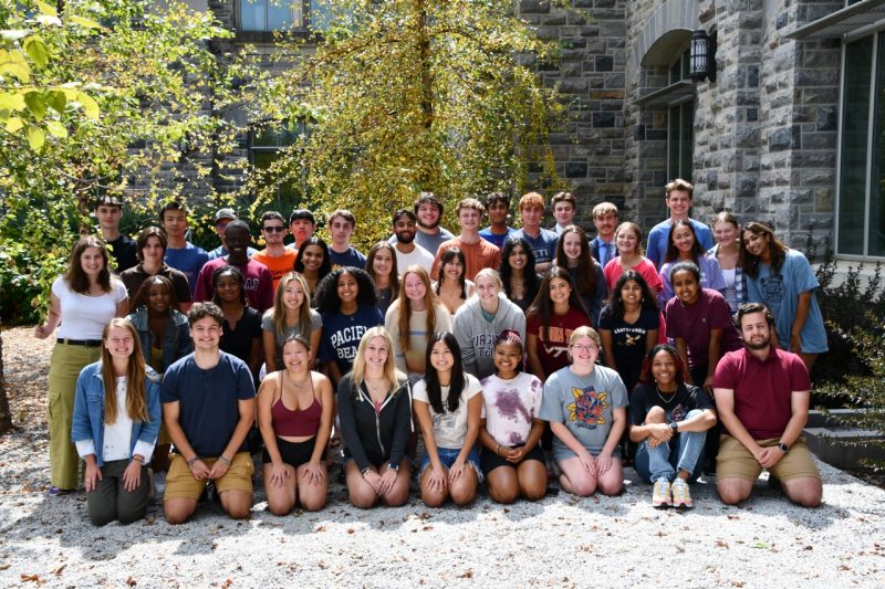 a large group of students gather and pose outside for a photo