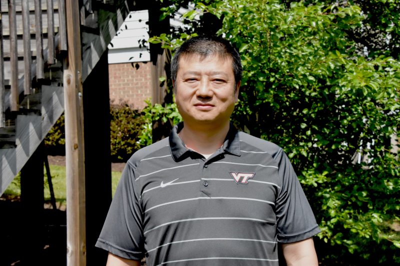 man poses in backyard wearing a VT polo shirt